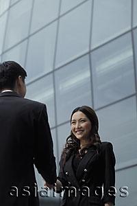 Asia Images Group - Man and woman shaking hands in front of building