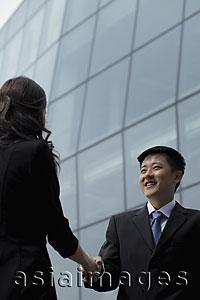 Asia Images Group - Man and women wearing suits shaking hands