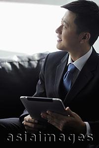 Asia Images Group - Young man wearing a suit holding a tablet