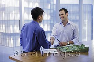 Asia Images Group - Young men shaking hands in modern office