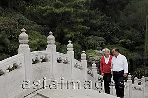 Asia Images Group - Older couple walking up a stone bridge