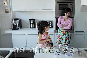 Asia Images Group - Mother watching her daughter cook in the kitchen