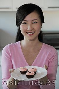 Asia Images Group - Young woman holding plate of cupcakes