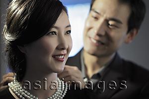 Asia Images Group - Young man putting a pearl necklace on a woman
