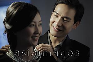 Asia Images Group - Young man putting on a pearl necklace on a woman