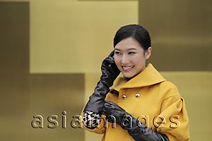 Asia Images Group - Young woman in coat and gloves talking on phone