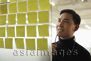 Asia Images Group - man looking at sticky notes and smiling