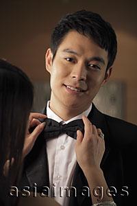 Asia Images Group - Young man getting his bow tie straightened by a woman