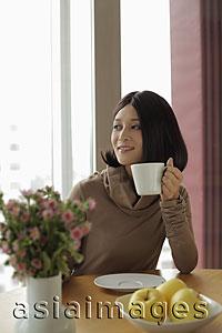 Asia Images Group - Young woman holding coffee looking out the window