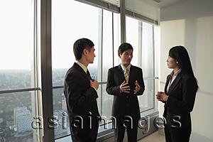 Asia Images Group - Three businesspeople talking in front of a window