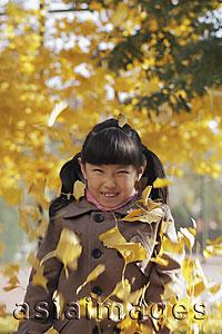 Asia Images Group - Autumn leaves falling on young girl
