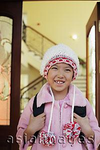 Asia Images Group - Young girl leaving her house in knitted hat and pink coat