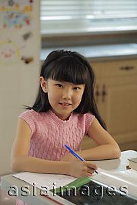 Asia Images Group - Young girl studying in the kitchen
