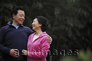 Asia Images Group - A senior couple in sweatsuits looking at each other and smiling