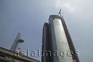 Asia Images Group - Low angle of modern skyscraper being built and Bitexco Financial Tower in background. Ho Chi Minh, Vietnam