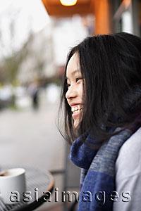 Asia Images Group - Head shot of young woman laughing at a cafe
