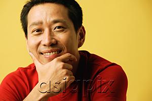 AsiaPix - Man smiling at camera, hand on chin, portrait