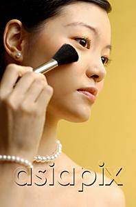 AsiaPix - Woman putting on blusher with make up brush