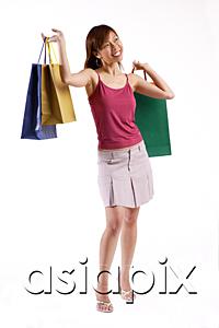 AsiaPix - Woman standing, carrying shopping bags in both hands, looking away