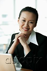 AsiaPix - Businesswoman smiling at camera, hands clasped