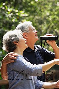 AsiaPix - Senior couple side by side, man holding binoculars