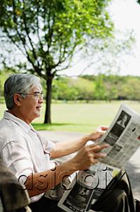 AsiaPix - Senior man reading newspaper in park