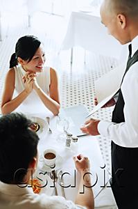 AsiaPix - Waiter showing menu to couple at restaurant