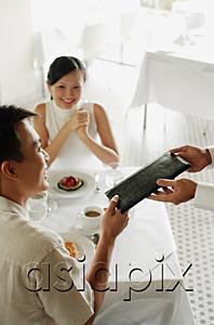 AsiaPix - Man giving menu to waiter, woman sitting opposite him
