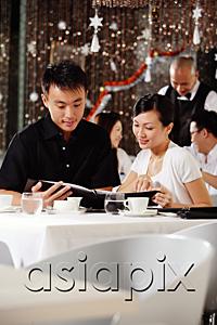 AsiaPix - Couple in restaurant, looking through menu, people in the background