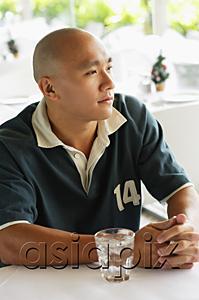 AsiaPix - Man looking away, glass of water on table next to him