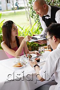 AsiaPix - Couple in restaurant, woman giving credit card to waiter