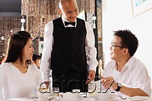 AsiaPix - Couple in restaurant, waiter standing and smiling at them