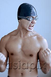 AsiaPix - Man wearing swimming cap and goggles, making fists and grimacing