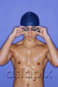 AsiaPix - Man wearing swimming cap and goggles, adjusting goggles