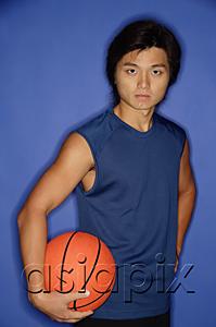 AsiaPix - Man holding basketball under arm, looking at camera