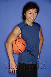 AsiaPix - Man holding basketball under arm, looking at camera, smiling
