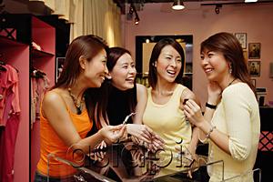 AsiaPix - Women at clothing store, watching one woman try on earrings, smiling