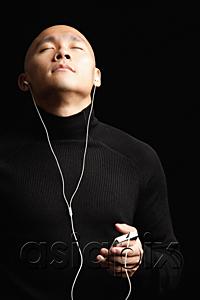 AsiaPix - Man with shaved head, listening to music with earphones, eyes closed