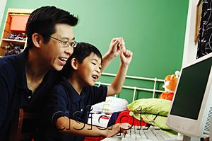 AsiaPix - Father and son looking at computer, raising hands