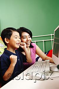 AsiaPix - Mother and son looking at computer, smiling