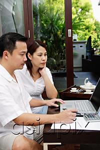 AsiaPix - Couple in living room, looking at laptop