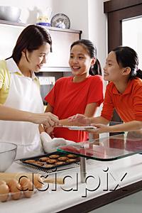AsiaPix - Mother and two daughters in kitchen, with tray of cookies