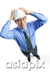 AsiaPix - Man wearing hardhat frowning, hands on head