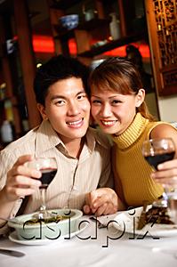 AsiaPix - Couple in restaurant, smiling at camera, holding wine glasses