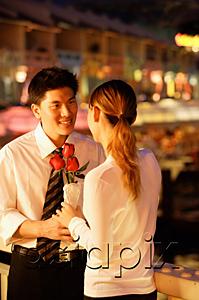 AsiaPix - Couple standing face to face, woman holding roses
