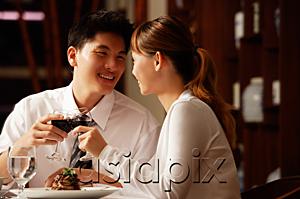 AsiaPix - Couple in restaurant, sitting side by side, toasting with wine glasses