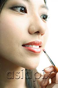 AsiaPix - Woman putting on lipstick with lip brush