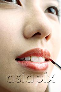 AsiaPix - Woman putting on lipstick with lip brush, close up