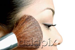 AsiaPix - Woman applying blusher with make-up brush, side view