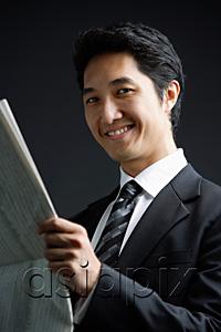 AsiaPix - Businessman holding newspaper, smiling